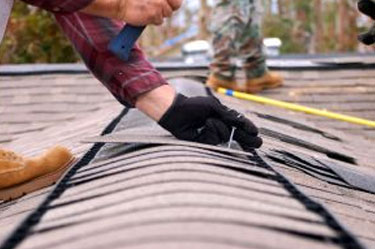 Roof Solutions Roofer nailing roof shingle on roof of home
